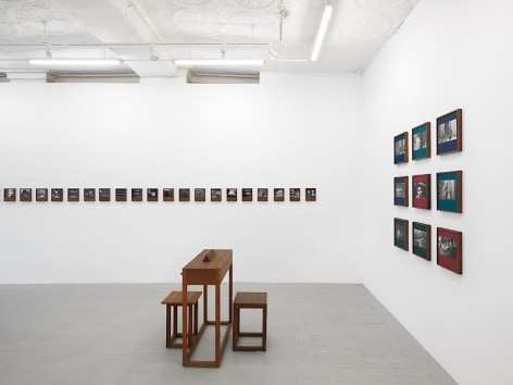 An installation view of Dayanita Singh's exhibition, which includes &quot;Pothi Boxes&quot; hung on the wall, &quot;Museum of Gestures,&quot; and a custom desk with 2 chairs.