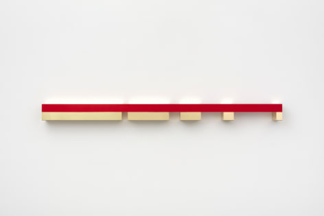 Donald Judd's untitled polished brass and red anodized aluminum sculpture, created 1974-75, installed on wall, measuring 5 x 75 x 5 in. (12.7 x 190.5 x 12.7 cm)