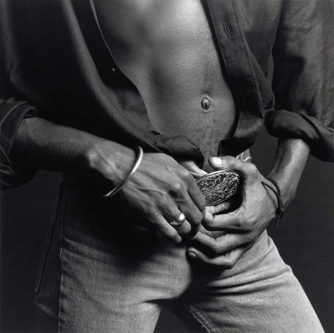 Black male wearing unbuttoned shirt and jeans, hands holding belt.
