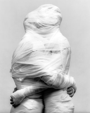 Two people wrapped together in white gauze.