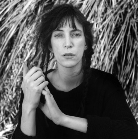 Portrait of Patti Smith, hands grasped.