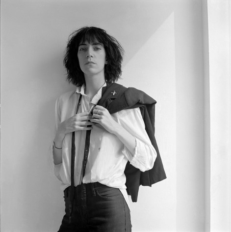 Patti Smith facing camera, suit jacket draped over shoulder.
