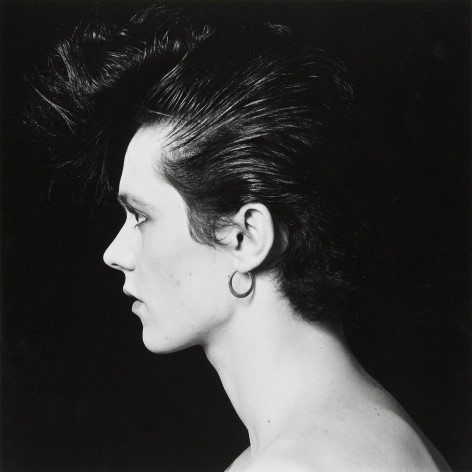 Portrait of a man in profile with slicked back hair wearing an earring.