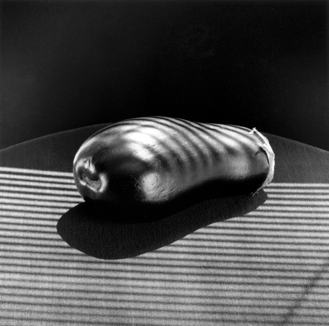 Eggplant laying on a cloth covered table with stripes of light beaming across it.