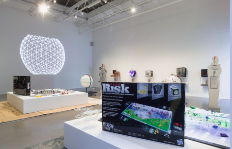 installation shot from Blockchain Futurue States at Petzel Gallery in 2016. features two risk game son pedestals and several case mods hanging on background wall.