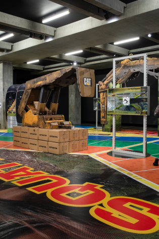 installation of MINE at MONA in 2020, featuring large vinyl on the floor that looks like a board game and a large cardboard sculpture of mining machinery standing on it.