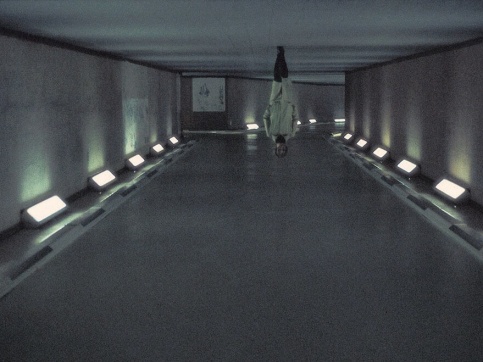 Photograph of a woman in a white coat walking in a hallway, turned upside-down