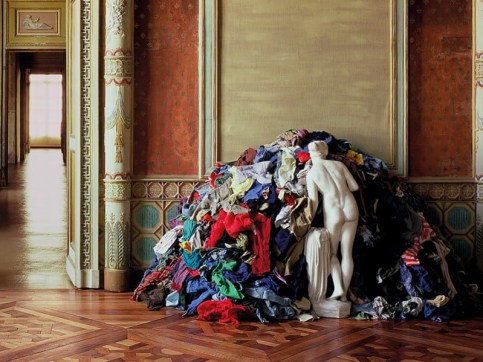 Plaster sculpture of a nude woman facing a mound of multi-colored rags