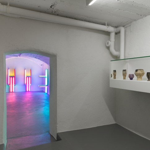 Installation view of fluorescent light sculptures by Dan Flavin and pottery by Lucie Rie and Hans Coper
