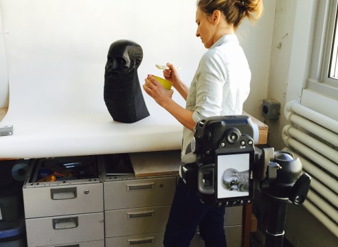 image of a woman holding a brush in front of a sculpture