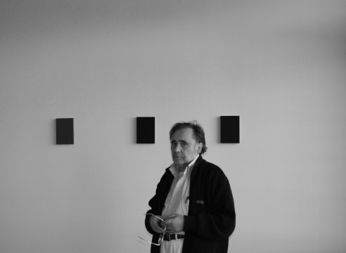 Black and white photo of Alfonso Fratteggiani Bianchi in front of three of his paintings