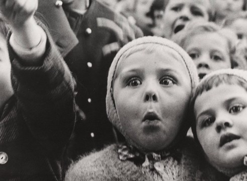 Black and white photo of a crowd of children reacting with excitement and astonishment.