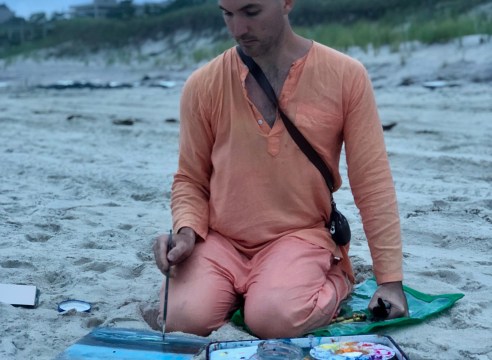 image of a man painting on a beach 