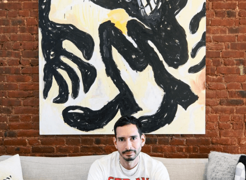 Rob Vargas in front of a Ricardo Gonzalez painting in his apartment