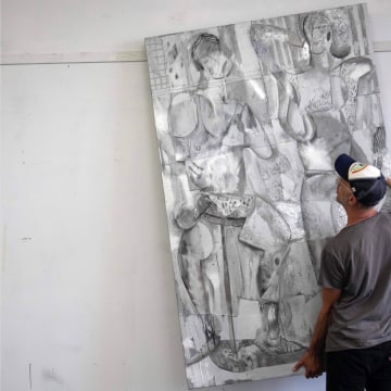 image of a man moving a large silver painting 