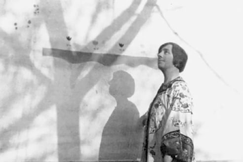 Photograph of Nell Brooker Mayhew in a kimono against a wall on which the shadow of a tree falls