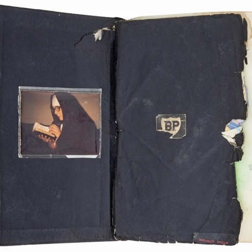 Black book open to first page. Left page: nun reading from book. Right page: letters "BP".