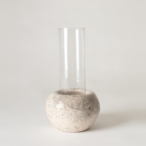 Clear glass tubular vase sitting inside raku ceramic holder. 