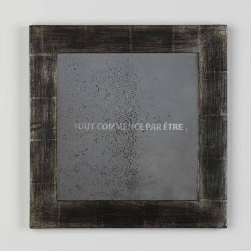 frame with the words 'tout commence par etre' written inside on a white wall