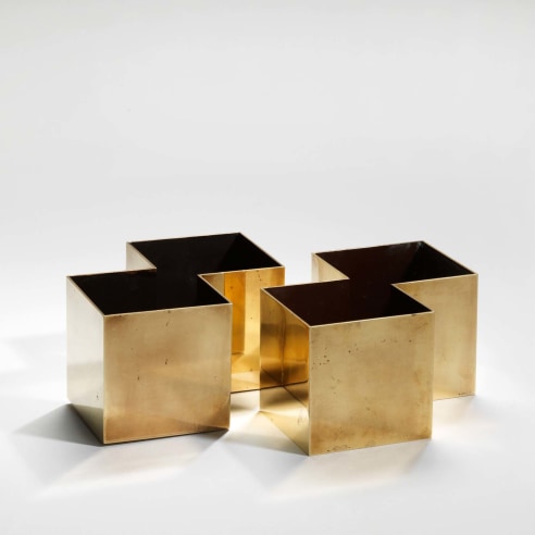 photograph of four gold square vases with black interiors in a blank room