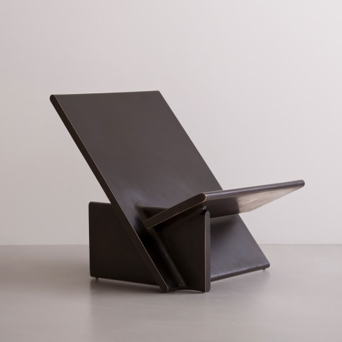 Blackened bronze lounge chair with intersecting planes