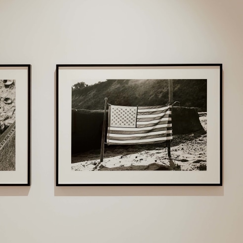 black and white photograph of the American flag on a beach