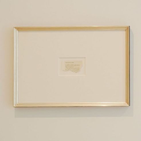 photograph of a framed newspaper clipping on a white wall
