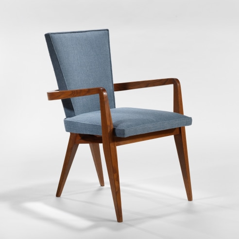 photograph of 1 chair in a blank room, chairs have wooden legs and blue upholstery 