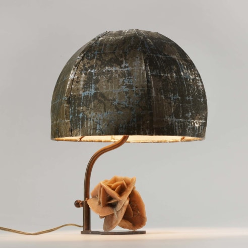 photograph of a lamp with a round shade and a sculpture of a rose at it's base