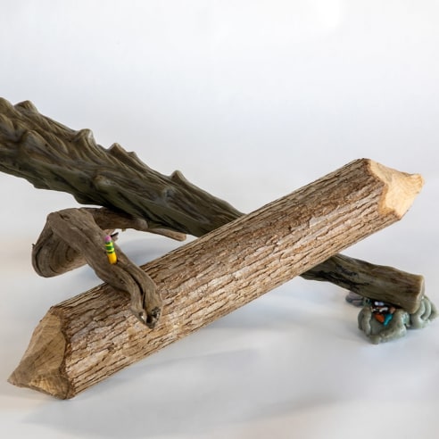 a sculpture by Lily Cox-Richard of a beaver-gnawed piece of wood, a plastic "wooden" club and a piece of driftwood in a triangular shape held together with a pencil 