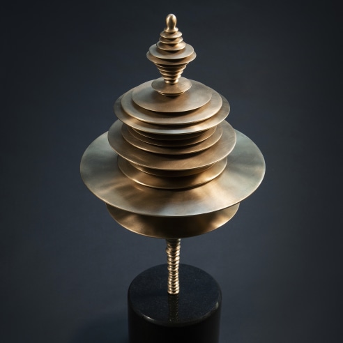 a bronze sculpture by Elizabeth Turk of discs stacked and arranged to simultaneously resemble a Modernist abstraction and a sound wave