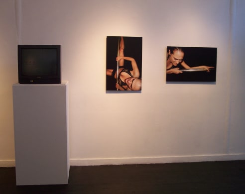 installation view of still photos next to tv playing video