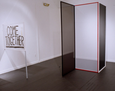 Artist made sign reading 'Come Together' with artist made glass box