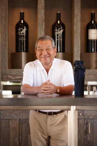 Kenzo Tsujimoto at Kenzo Estate Tasting Room counter with wine bottles