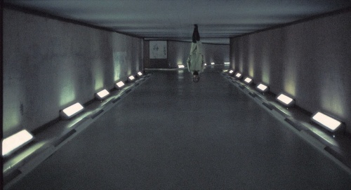 Photograph of a woman in a white coat walking in a hallway, turned upside-down