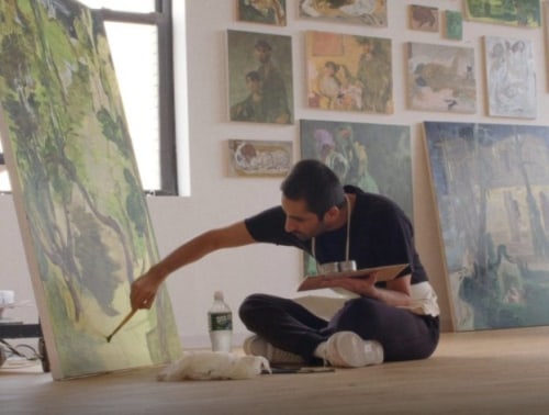 Male artist sitting on the floor working on a painting
