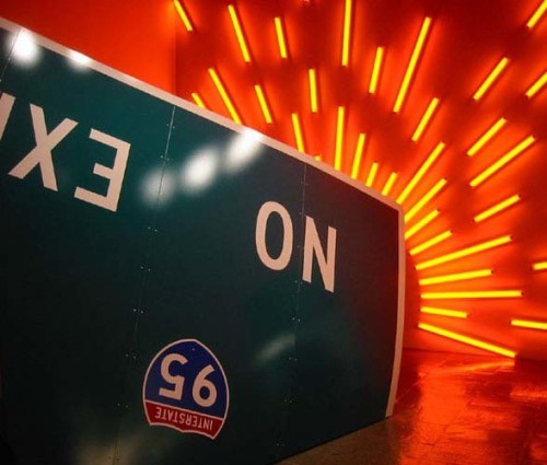 2 sculptures: a highway sign and neon light installation