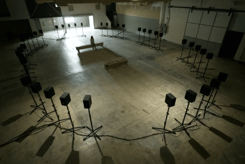 Sound installation in an empty warehouse with 40 speakers surrounding a central seating area