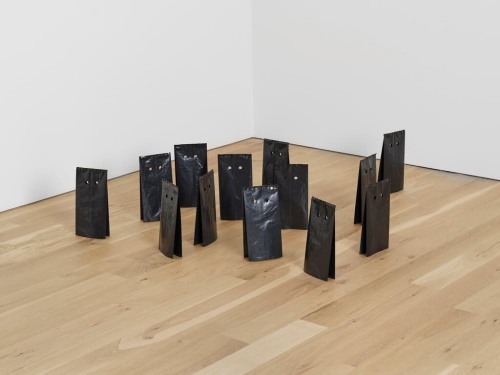 sculpture of multiple black bags on floor