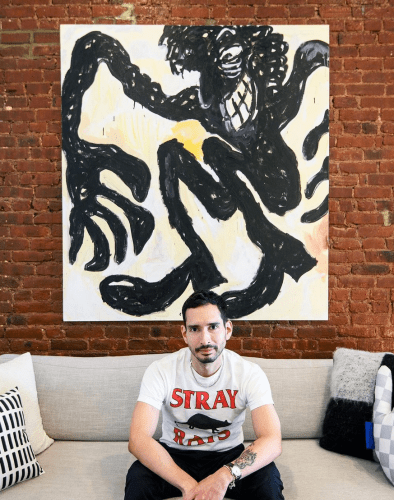 Rob Vargas in front of a Ricardo Gonzalez painting in his apartment
