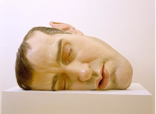 giant realistic head of a man laying on its side, as if he were asleep