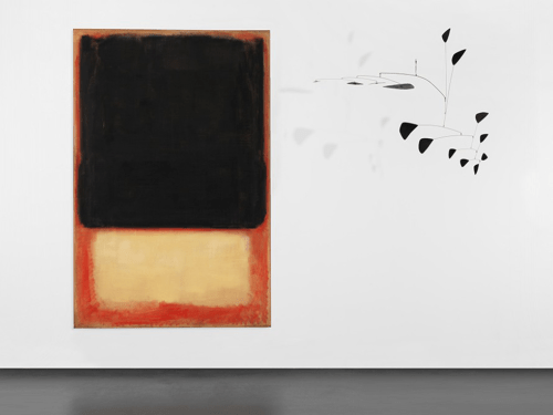 Installation view of a black and yellow Rothko painting next to a black mobile sculpture by Calder that is suspended from the ceiling.