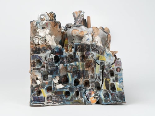 A mixed clay sculpture with images and decals upon it
