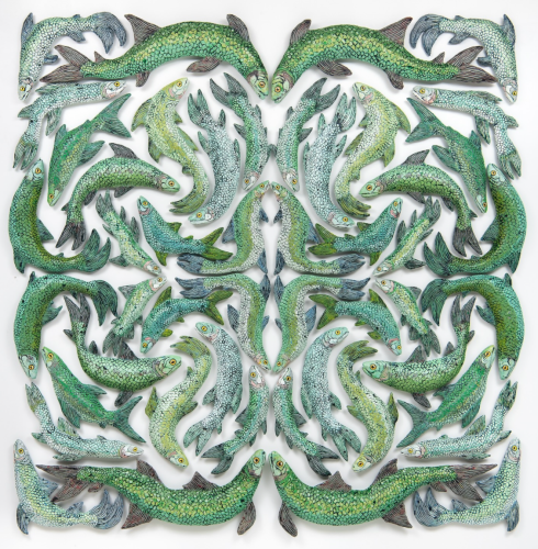 This is an image of an artwork by Zachary Armstrong. It consists of of many green wooden fish in a symmetrical pattern.