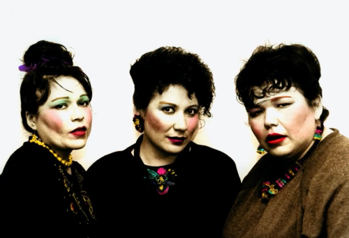 Three Native American women wear makeup and bouffant hairdos while they look at the camera.