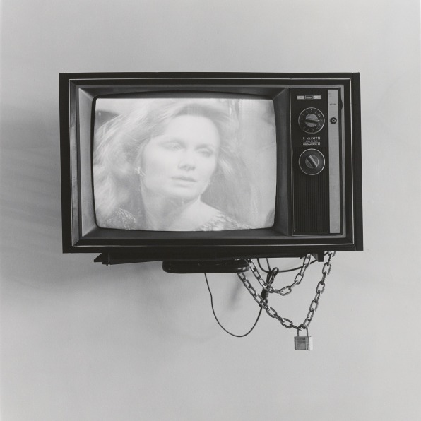 Television with woman on the screen, with lock and chain hanging off.
