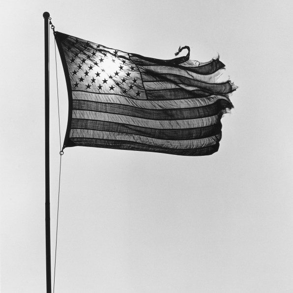 Backlit, tattered American flag flying in the wind.
