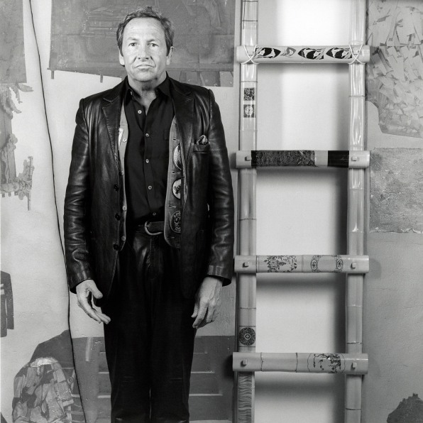 Portrait of Robert Rauschenberg standing next to ladder.