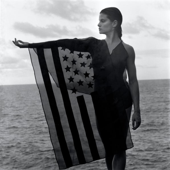Lisa Lyon standing in front of the ocean, wearing American flag dress.