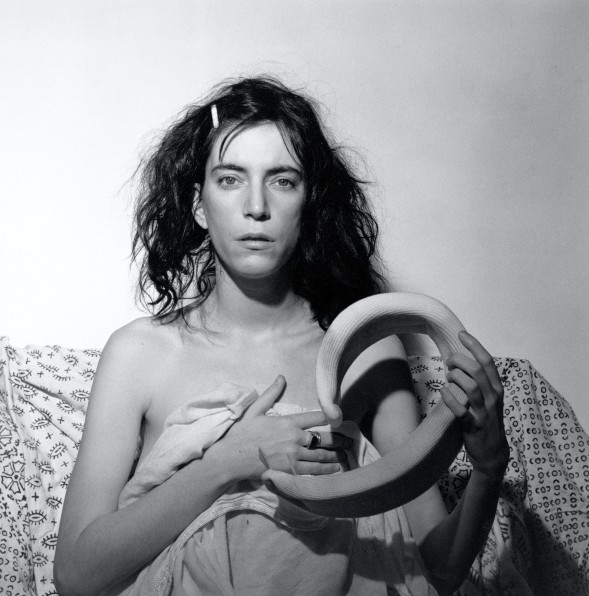 Patti Smith facing camera, wrapped in a sheet and holding neck brace.